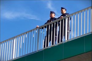 Dwaj policjanci stoją na wiadukcie i obserwują ćwiczenia.