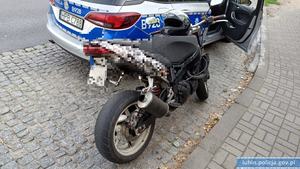 Motocykl stojący koło radiowozu policyjnego.