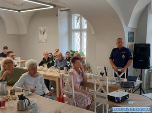 Policjant mówi do starszych mieszkańców Złotoryi o bezpieczeństwie.