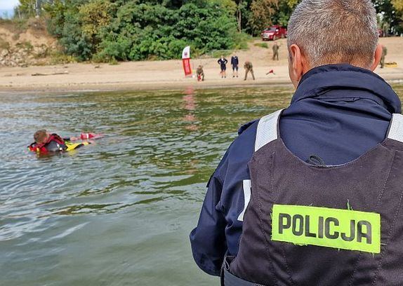 Policjant podczas ćwiczeń z łódki obserwuje jak żołnierze ratują tonącego człowieka