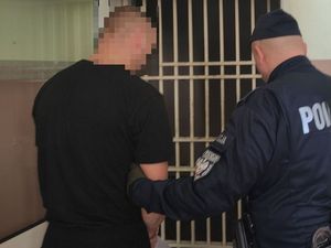 policjant prowadzi zatrzymanego