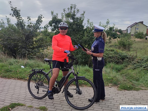 Policjantka stoi przy mężczyźnie na rowerze.
