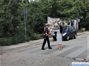 Policjantka na pasach zakłada kobiecie na rękę opaskę odblaskową.