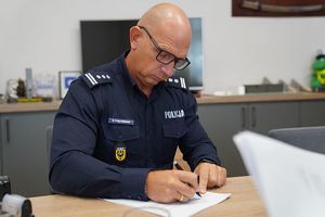 I Zastępca Komendanta Wojewódzkiego Policji inspektor Robert Frąckowiak podpisuje dokumenty siedząc przy biurku w gabinecie