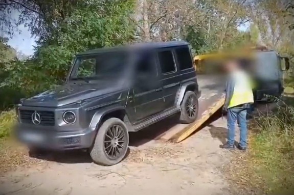 Odzyskany mercedes wjeżdża na lawetę z boku policjant