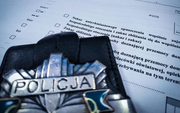 odznaka policyjna leżąca na aktach sprawy