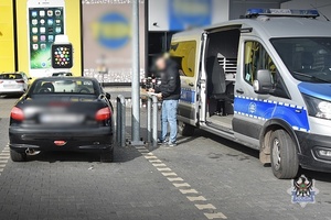 Bus policyjny stojący obok samochodu osobowego