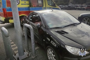 Czarny samochód osobowy a za nim stoi karetka pogotowia