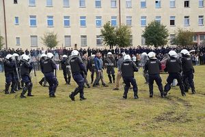 policjanci w białych kaskach i z tarczami stojący na murawie