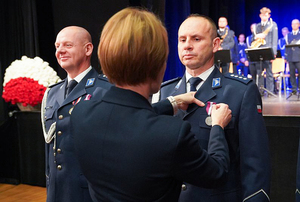 Przedstawicielka Wojewody dolnośląskiego przypina medal policjantowi.