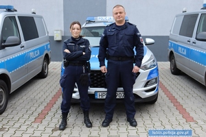 Policjanci stoją przed radiowozem
