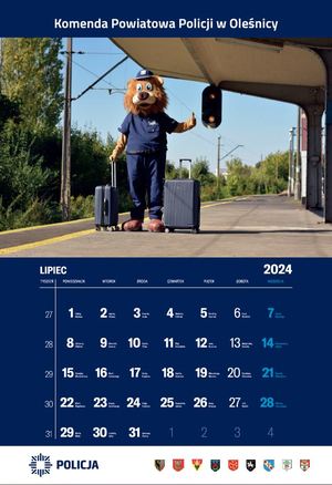 Kalendarz na lipec Komendy Powiatowej Policji w Oleśnicy - na zdjęciu komisarz lew maskotka policyjna z walizką na peronie