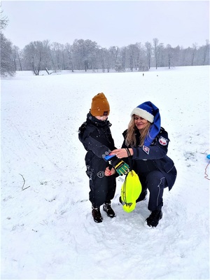 Policjantka zakłada odblask na rękę chłopcu w kombinezonie zimowym