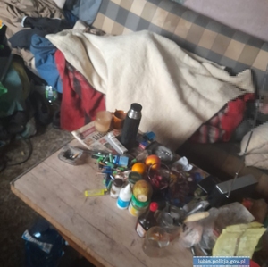 Mężczyzna leżący pod kocami w zaniedbanym pomieszczeniu