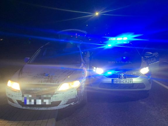radiowóz i stojący obok inny pojazd na drodze