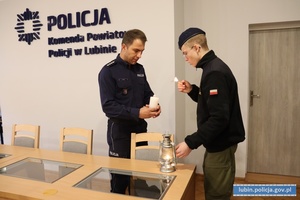 Harcerz przekazuje światełko pokoju policjantowi