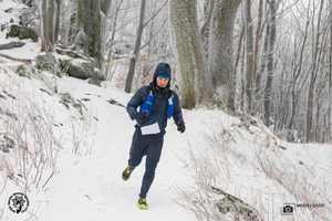 Mężczyzna w stroju zimowym sportowym biegnący po śniegu