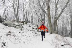 Mężczyzna w stroju zimowym sportowym biegnący po śniegu z tyłu kolejny zawodnik