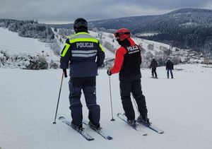 Dwaj policjanci na nartach znajdujący się na stoku