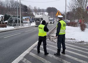 Kontrola drogowa - policjant mierzący prędkość nadjeżdżających pojazdów, obok stoi inspektor ruchu drogowego