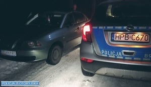 radiowóz stojący koło samochodu osobowego