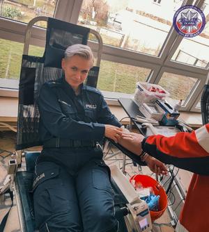 Policjantka siedząca na fotelu i pielęgniarka pobierająca jej krew
