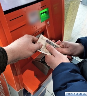 Jedna ręka wyrywa pieniądze z drugiej ręki przy bankomacie