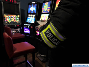 policjant stojący w salonie gier koło automatów