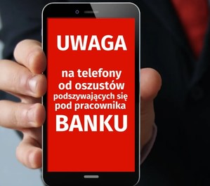 Na zdjęciu widoczny telefon komórkowy na wyświetlaczu napis &quot;Uwaga na telefony od oszustów podszywających się pod pracownika banku&quot;.