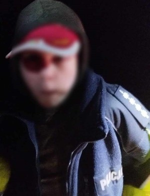 Na zdjęciu widoczny 12-latek znaleziony przez policjanta w komplecie leśnym. Chłopiec posiada założoną na głowę czapkę z daszkiem oraz założony ciemny polar na napisem Policja. twarz dziecka jest rozmazana celem uniemożliwienia jego identyfikacji.