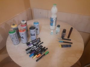 Farby, spraye i flamastry do malowania graffiti leżące na stole