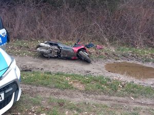 Przewrócony motocykl na polu obok radiowóz