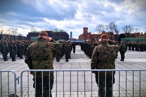 Zdjęcie z robione z tyłu salutujących żołnierzy podczas uroczystego apelu