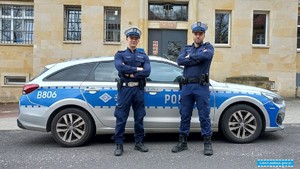 Dwaj policjanci stojący przy radiowozie