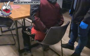 Zatrzymany meżczyzna siedzący przy stole podczas przesłuchania