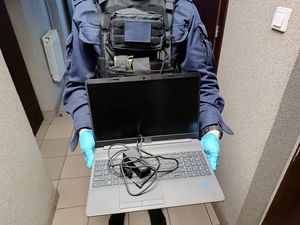 Policjant trzymający odzyskany laptop