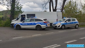 Dwa radiowozy i policjanci przeszukujący białego busa