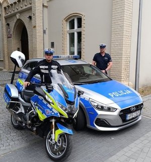 policjanci przy radiowozie i motocyklu