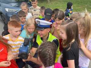 Policjant pokazuje dzieciom ręczny miernik prędkości