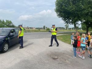 Dzieci wraz z policjantami kontrolują przejeżdżający pojazd