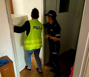 Dwie policjantki wstawiają lodówkę do pomieszczenia