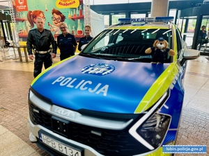 dwie policjantki o policjant ruchu drogowego stojący przy radiowozie