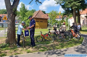 Policjant wręcz dziecku na rowerze torbę z podarunkami