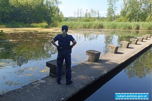 policjantka stoi na betonowym pomoście nad akwenem wodnym