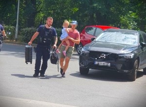 Policjant wraz z mężczyzną trzymającym na rękach dziecko