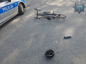 zniszczony rower po wypadku leży na ulicy koło niego stoi radiowóz