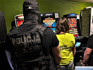 policjant i strażniczka służby celno skarbowych stojący koło automatów do gier