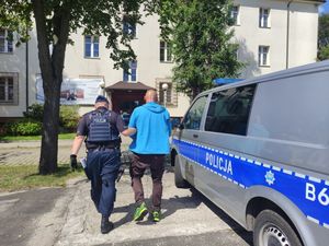 Policjant prowadzi zatryzmanego mężczyznę