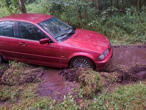 czerwone BMW w leśnym błocie - widok z boku