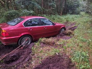 czerwone BMW w leśnym błocie - widok z tyłu